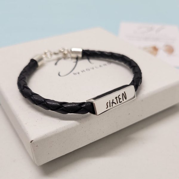 ett svart läderarmband med silver berlock som vi graverat med en namnteckning