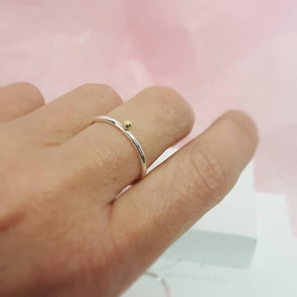 Liten 1,5mm slät silverring med en guldkula på hand